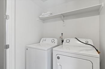 Two white front loading washing machines in a small laundry room.